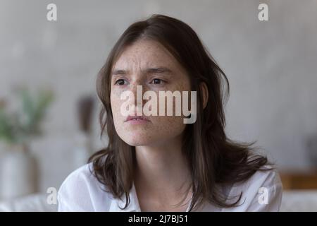 Thoughtful girl with freckled facial skin lost in deep thoughts Stock Photo