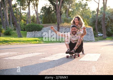 Young cool tattooed couple having fun skateboarding. Stock Photo