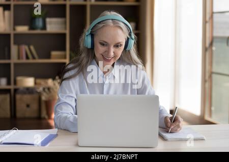 Happy mature training course student woman in wireless earphones Stock Photo