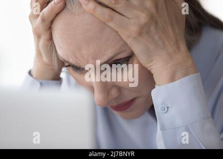 Concerned stressed mature business lady touching head Stock Photo