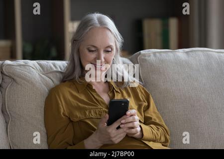 Happy focused senior cellphone user woman reading text message Stock Photo