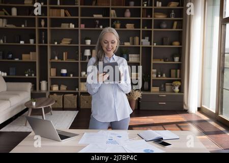 Happy senior freelance business woman using tablet computer Stock Photo