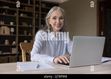 Happy senior online teacher woman using laptop computer Stock Photo