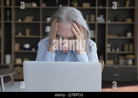 Tired frustrated senior business woman suffering from headache Stock Photo
