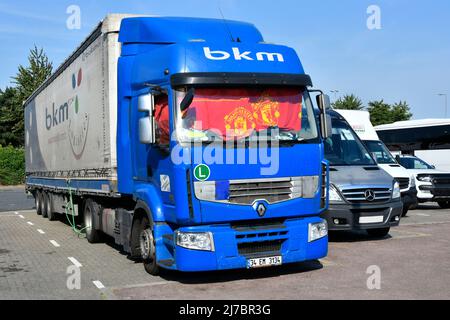 BKM Turkish blue Renault hgv lorry truck & trailer parked for sleep break UK motorway services red Manchester United supporters curtain in cab window Stock Photo