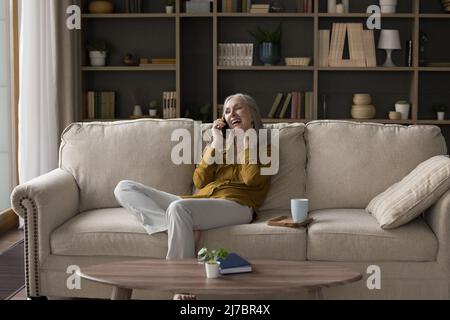 Cheerful excited mature smartphone user woman talking on cell Stock Photo