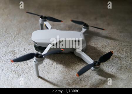 Small gray quadcopter on a gray background. Quadrocopter close-up. Stock Photo