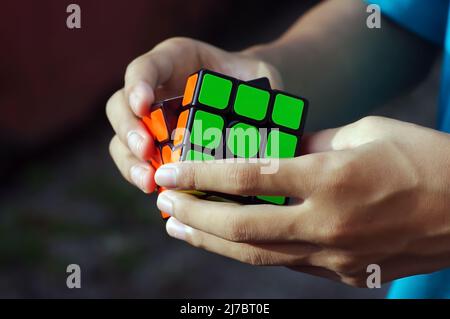 A child playing a colorful rubik cube puzzle Stock Photo