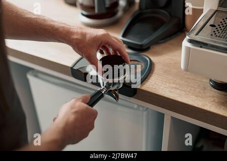 Barista pressing ground coffee into portafilter with tamper Stock Photo