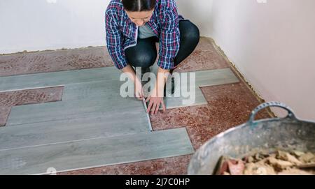 Female bricklayer measuring tiles to install a floor Stock Photo