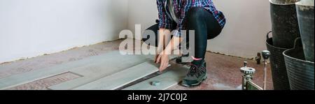 Female bricklayer placing tiles to install a floor Stock Photo