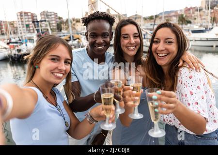 Group of multiracial people having fun together drinking champagne on boat Stock Photo