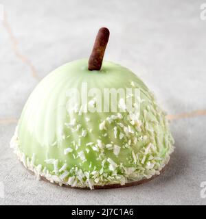 French mousse cake covered with green glazeon a stone background. Luxury apple dessert. Stock Photo