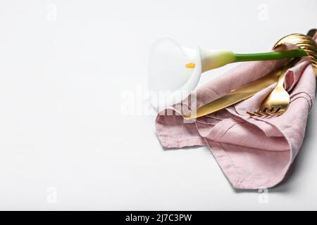Golden cutlery and beautiful calla lily on white background, closeup Stock Photo