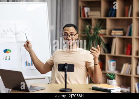 Young arab man making business presentation and demonstrating graphs on whiteboard Stock Photo