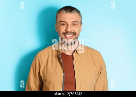 Portrait Of Happy Middle Aged Man Over Blue Background Stock Photo