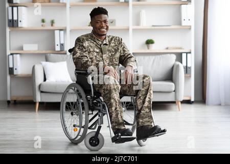Happy black soldier sitting in wheelchair, clinic interior Stock Photo