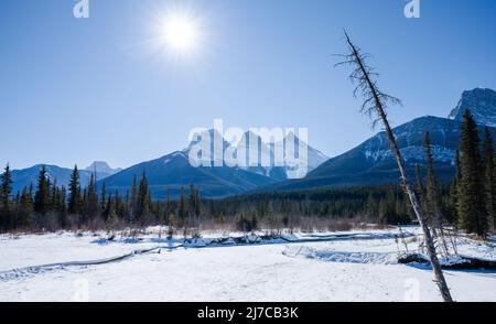 Snow capped Three Sisters ridge and Mount Lawrence Grassi mountain range during winter. Canadian Rockies beautiful scenery. Canmore, Alberta, Canada. Stock Photo