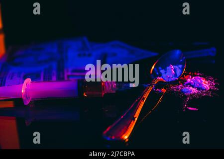 Money and drugs. Banknotes, simulation of drugs such as heroin or cocaine, syringe on a black, illuminated surface suggesting the forbidden, illegal, Stock Photo