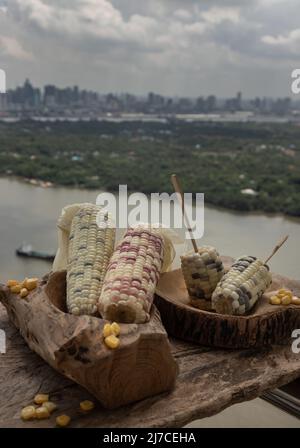 Fresh waxy corn or Sweet glutinous corn and Corn kernels on Wood cross section over Rustic old wooden table with City and River view. Tropical whole g Stock Photo