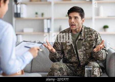 Emotional soldier sharing his thoughts with woman psychotherapist Stock Photo