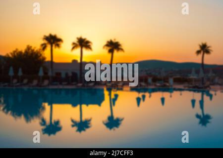 Palm trees reflection in turquoise water on a tropical seaside during sunset. Natural background blurring.  Stock Photo