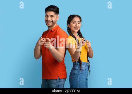 Gotcha. Young arabic couple pointing at camera with fingers and laughing Stock Photo