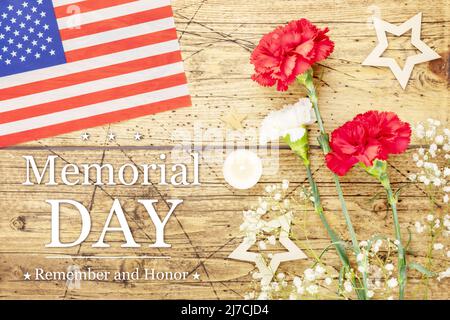 Memorial Day card. American holiday banner with bouquet of carnations, American flag, stars and candle on a wooden background with inscription Memoria Stock Photo