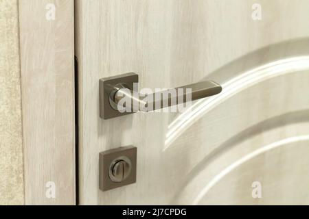 Metal door handle or doorknob with security lock on wooden background Stock Photo