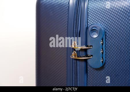 Combination lock and blocked zippers on a blue travel suitcase on a white background close-up. Travel safety. Stock Photo