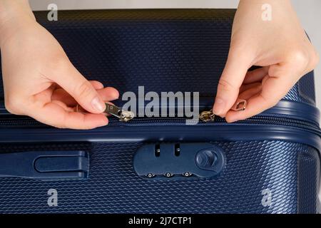 A hands and a combination lock on the suitcase. Zipper slider lock, close-up. Stock Photo