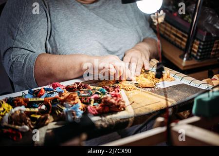 Senior elderly female hands embroider choose cotton craft threads. Handmade cross stitch embroidery in women s hands. Cross stich set in process Stock Photo