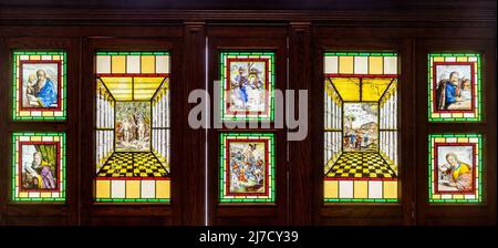 17th century Flemish painted glass, collection of paintings set into a wooden cabinet in St Bartholomew's Church, Haslemere, Surrey, England, UK Stock Photo