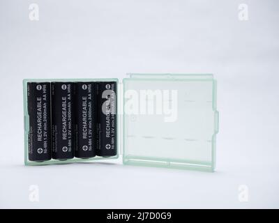 Green translucent plastic case holding four AA type rechargeable batteries  white background Stock Photo