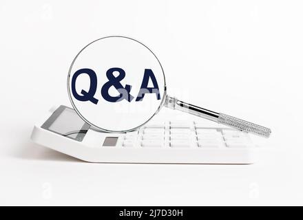 Calculator and magnifying glass with qa abbreviation. Search for answers to questions in business, statistics, finance field. High quality photo Stock Photo