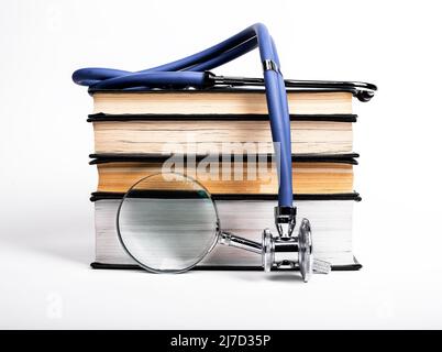 Books stack with stethoscope and magnifying glass. Medical data search and learning, preparing for examination, conducting research in medicine area. High quality photo Stock Photo