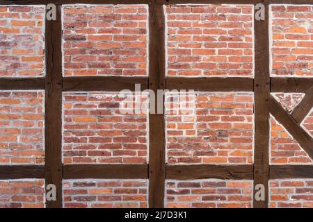 Wall of a half timbered house as abstract background texture. Building exterior with traditional architecture. An old facade with bricks and planks. Stock Photo