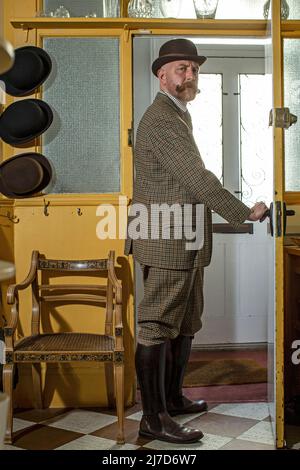 Well dressed English gentleman leaving his house wearing a bowler hat . Stock Photo