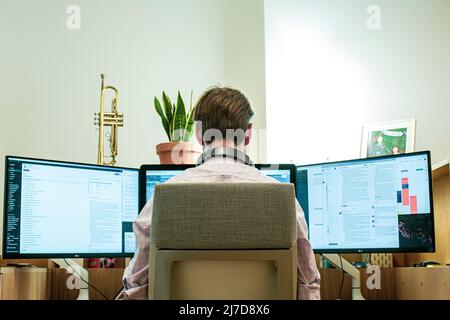 casual young man with headset using computer in a office. Back view. Stock Photo
