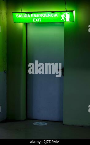 Door with illuminated emergency exit sign, in Spanish and English. Stock Photo