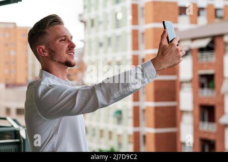 Young executive businessman using a mobile phone while standing on a balcony. Stock Photo
