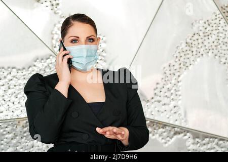 Executive woman using a face mask while talking on the mobile phone. Stock Photo