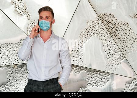 Executive man using a face mask while talking on the mobile phone. Stock Photo