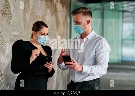 Coworkers wearing face masks while discussing about business in the office. Stock Photo