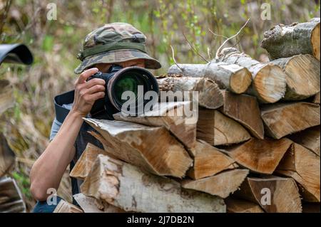 Female paparazzi detective taking pictures from the hide. Stock Photo