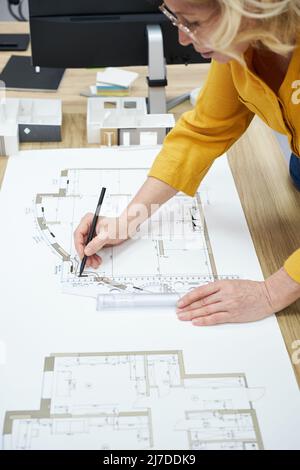 Close-up of mature female architect drawing project with pencil and ruler at table Stock Photo