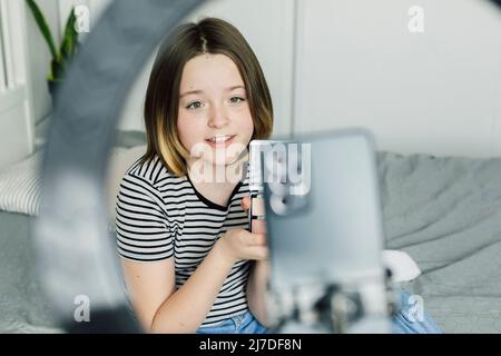 Teen girl making video blog on smartphone with use LED lamp. Lifestyle beauty blogging concept Stock Photo