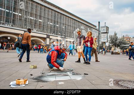 A street artist paints a realistic portrait on the floor of a city square. Street art. Berlin, Germany - 05.17.2019 Stock Photo