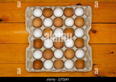 Chicken eggs in a package on the table. Brown and white chicken eggs in the egg tray in a checkerboard pattern. Natural eco-friendly products. Fresh Stock Photo