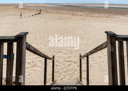 View out to sea over a deserted beach from a beach hut at Wells-next-the-Sea on the North Norfolk coast. Steps raise the entrance above beach level. Stock Photo